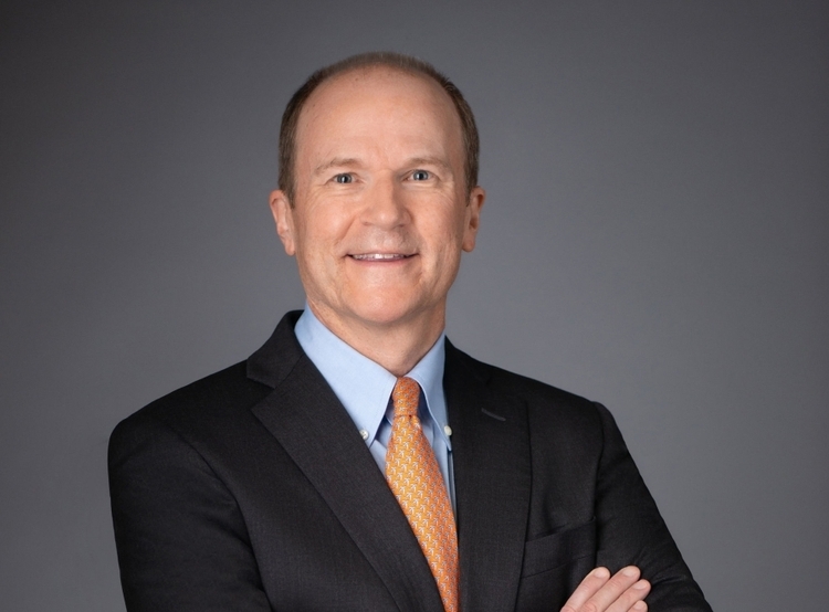 White male in a suite with a dark background